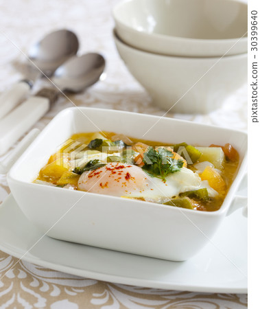 Fish stew with coriander leaves an a poached egg 30399640