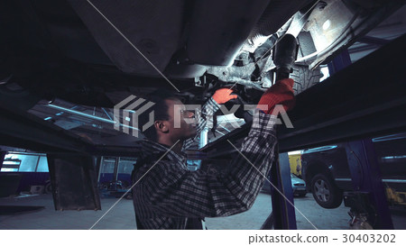African mechanic working on the underside of a car African mechanic working on the underside of a car 30403202