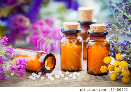 Bottles of homeopathic globules and healing herbs 30406292