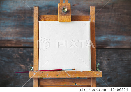 Empty canvas on easel on old wooden background. 30406304