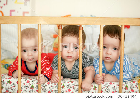Portrait of newborn triplets in the bed Portrait of newborn triplets in the bed 30412404
