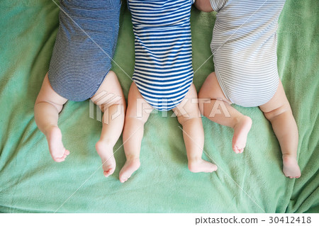 Newborn triplets lie on a stomach on a blanket 30412418
