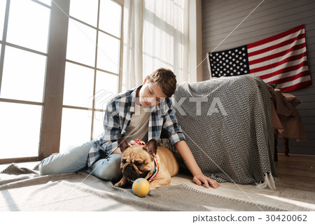 Delighted teenager sitting near his best canine 30420062