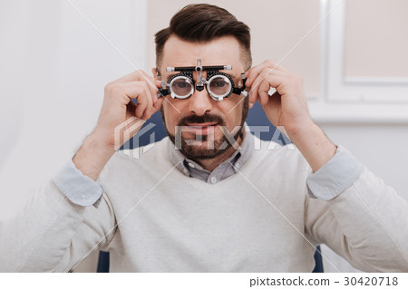 Pleasant good looking man holding eye examination 30420718