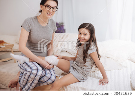 Joyous mother bandaging her child knee at home 30421689