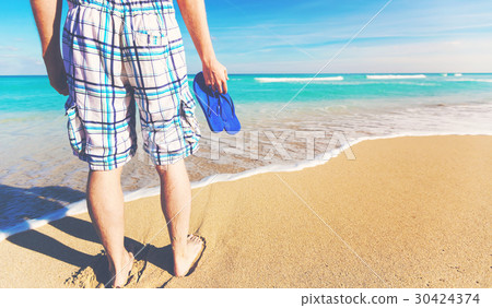 Man holding his sandals at the shore 30424374