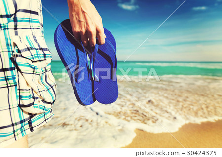 Man holding his sandals at the shore 30424375