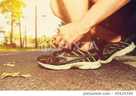 Male jogger tying his running shoes Male jogger tying his running shoes 30424394