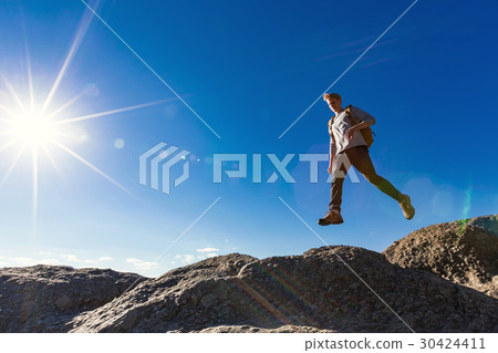 Man jumping over gap on mountain hike 30424411