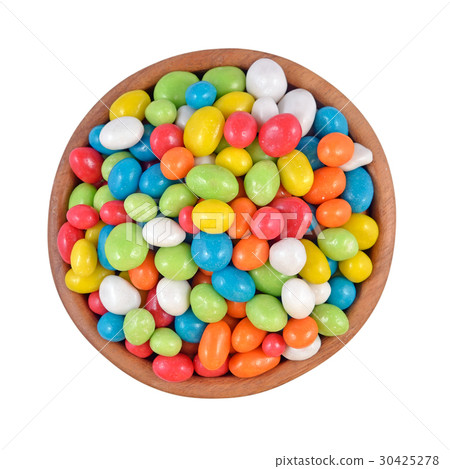 Candy sea pebbles in a wooden bowl on a white Candy sea pebbles in a wooden bowl on a white 30425278