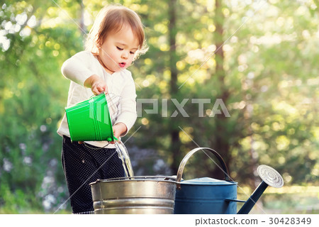 Happy toddler girl playing with watering cans Happy toddler girl playing with watering cans 30428349