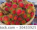 Red rambutan on brown wicker basket. 30433925