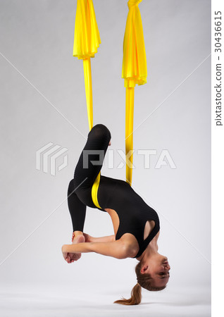 Flexible woman practicing fly yoga in studio 30436615