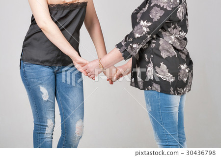 Daughter and mother stand together holding hands Daughter and mother stand together holding hands 30436798