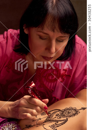 Mehendi artist paints an ornament of henna Mehendi artist paints an ornament of henna 30438255