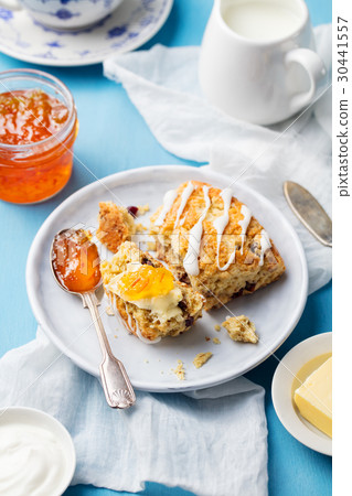 Scone with jam and butter on plate Blue background Scone with jam and butter on plate Blue background 30441557