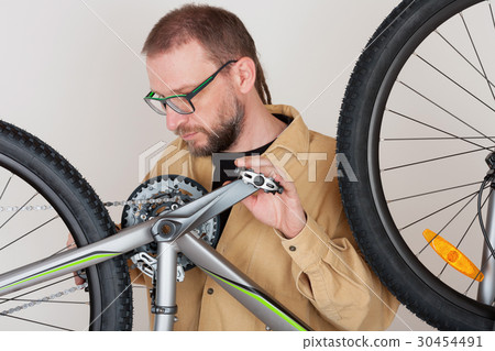 Bearded man checks the fastening of rear wheel  30454491