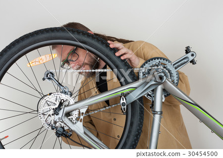 Bearded caucasian man repairing  the mtb bicycle 30454500