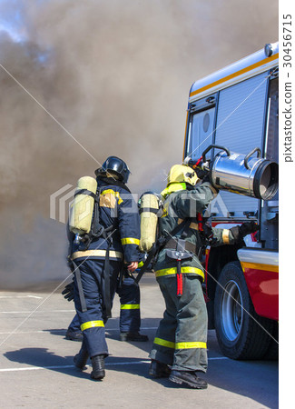 Team firefighters extinguish a fire in the smoke Team firefighters extinguish a fire in the smoke 30456715