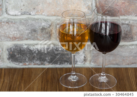 Glasses of red and white wine on rustic brick wall 30464845