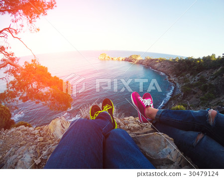Couple legs hanging over rocks Couple legs hanging over rocks 30479124
