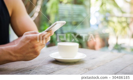 Man using a smartphone in a coffee shop. 30486185