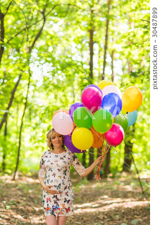 Young pregnant woman holding colorful balloons Young pregnant woman holding colorful balloons 30487899