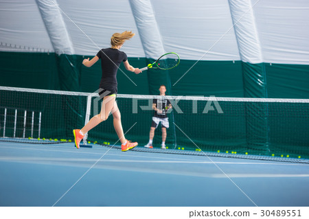 The young girl in a closed tennis court with ball 30489551