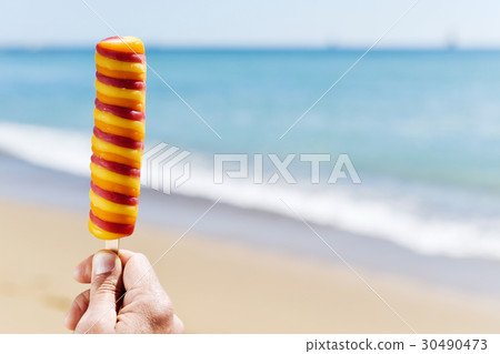 man eating a popsicle on the beach 30490473