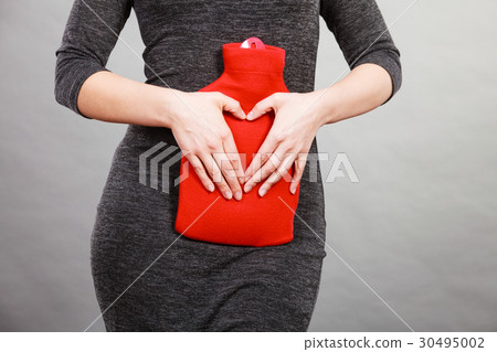 Girl holds hot water bottle on belly making heart shape by hands 30495002