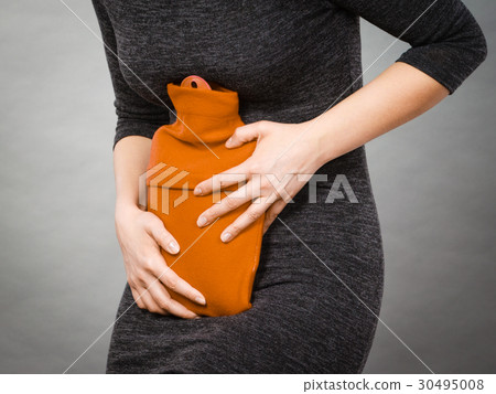 Girl having stomach ache, holding hot water bottle 30495008