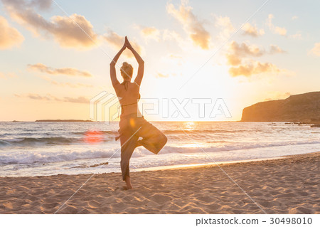 Woman practicing yoga on sea beach at sunset. 30498010