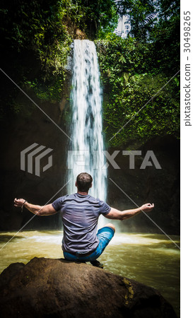 Man meditating in front of waterfall near Ubud Man meditating in front of waterfall near Ubud 30498265