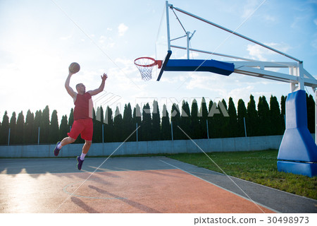 Young man jumping and making a fantastic slam dunk 30498973