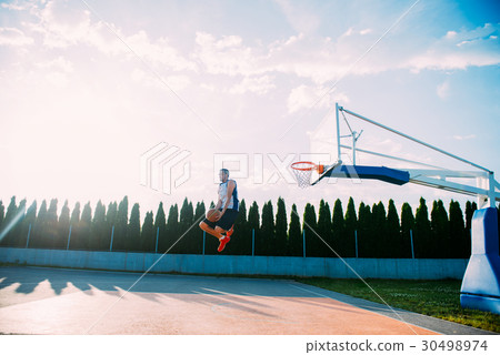Young man jumping and making a fantastic slam dunk 30498974