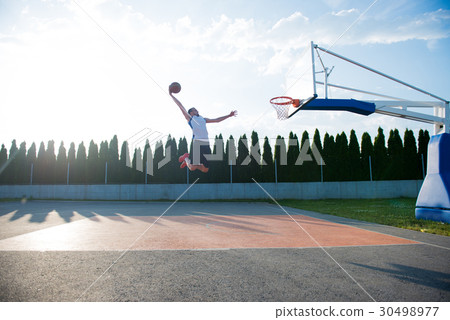 Young man jumping and making a fantastic slam dunk Young man jumping and making a fantastic slam dunk 30498977