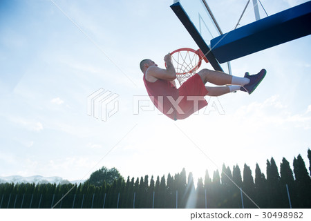 Young man jumping and making a fantastic slam dunk 30498982