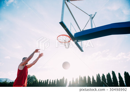 Young man jumping and making a fantastic slam dunk 30498992