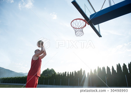 Young man jumping and making a fantastic slam dunk 30498993