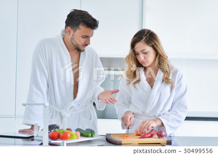 Happy couple cooking breakfast together in the Happy couple cooking breakfast together in the 30499556