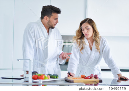 Happy couple cooking breakfast together in the Happy couple cooking breakfast together in the 30499559