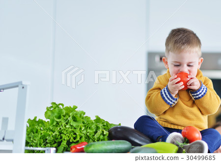kid girl eating healthy vegetables at kitchen 30499685