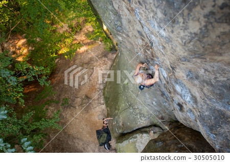 Woman rockclimber is reaching top of the rock 30505010
