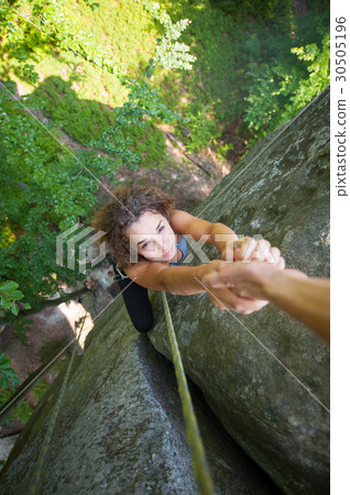 Girl climbing on big rock and hanging on the hand 30505196