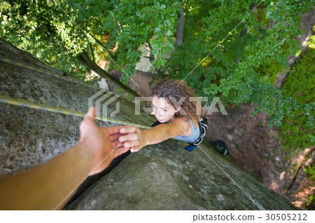 Girl climbing on big rock and hanging on the hand 30505212