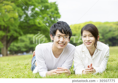 Couples Lifestyle Lying on the lawn of a fresh green park Looking at the camera Couples Lifestyle Lying on the lawn of a fresh green park Looking at the camera 30507775