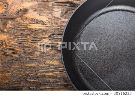 a cast-iron frying pan on a wooden background 30516223