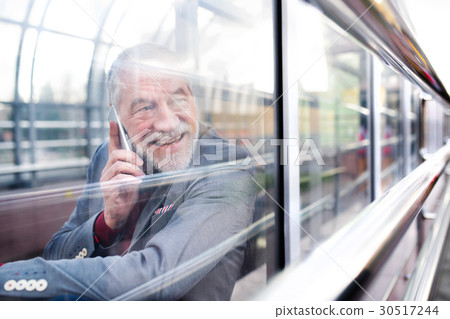 Senior man with smartphone in glass passage making Senior man with smartphone in glass passage making 30517244