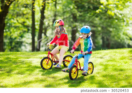 Kids ride balance bike in park Kids ride balance bike in park 30520453