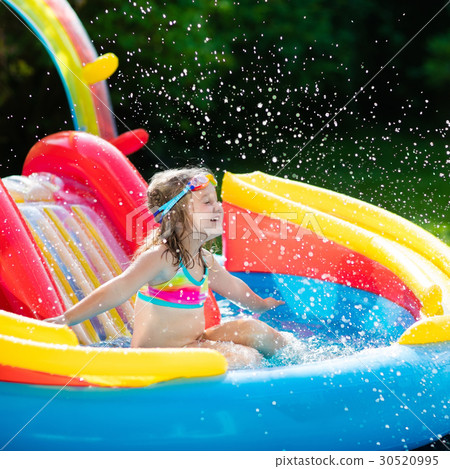 Child in garden swimming pool with slide 30520995